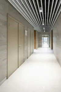 An unfinished residential basement with exposed concrete walls and floor, a white six-panel door, and framing for wooden stud walls and the ceiling joists overhead.