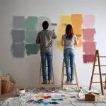 Homeowners testing paint colors on a wall while learning how to plan interior painting projects before repainting their home