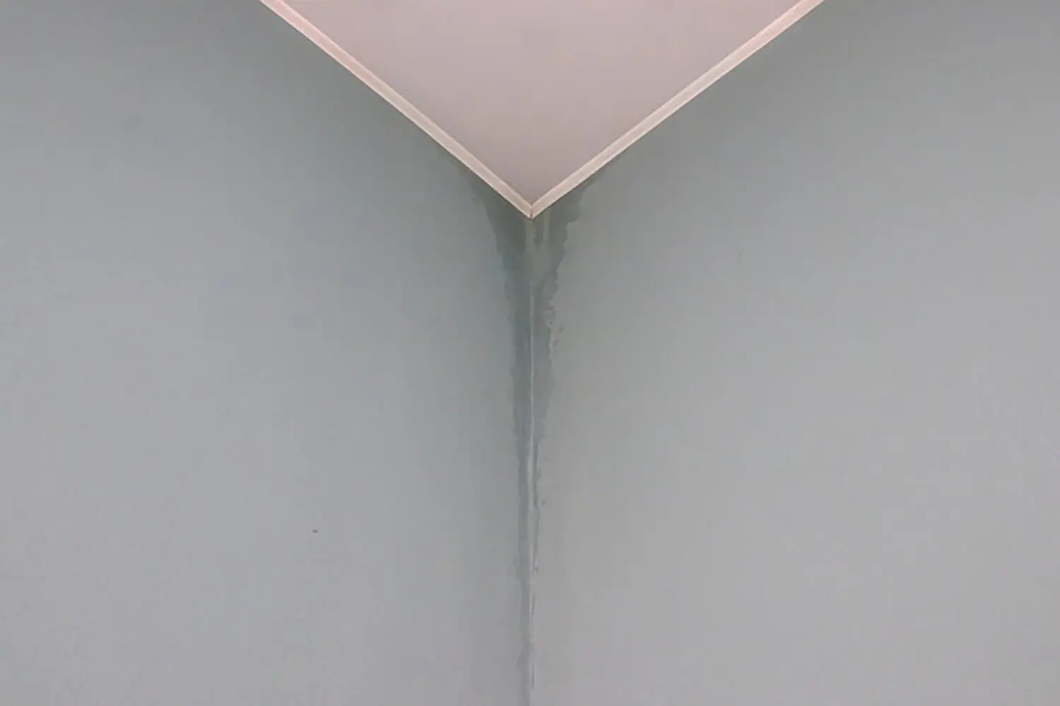 Water stains and uneven paint finish showing how humidity affects interior paint drying on an interior wall corner