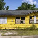 Abandoned Florida home with severely peeling and faded yellow exterior paint, showing the kind of surface damage that causes exterior paint to fade faster on homes in Naples and throughout Southwest Florida.