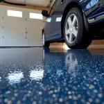 Freshly coated epoxy garage floor in a Fort Myers home with a blue chip finish and parked vehicle, showing how long epoxy garage floors last when professionally installed.