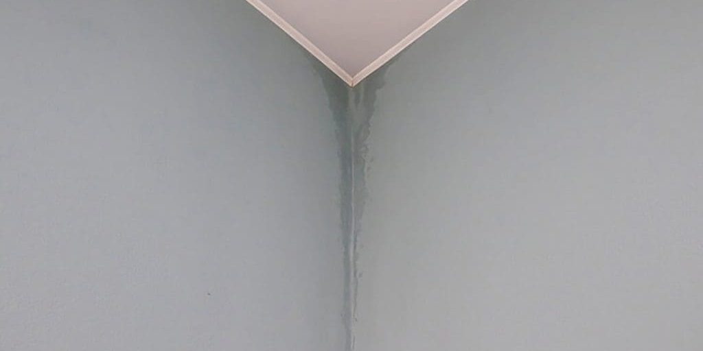 Water stains and uneven paint finish showing how humidity affects interior paint drying on an interior wall corner